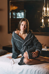 Fototapeta premium Young charming girl in a gray bathrobe waiting for procedure. beautiful woman spending time at modern spa cabinet for relaxing