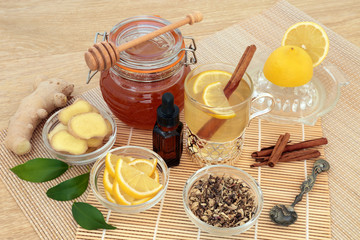 Natural flu and cold remedy ingredients with echinacea herb, eucalyptus oil, fresh ginger, lemon fruit, cinnamon sticks and honey with natural medicinal hot drink on bamboo background.