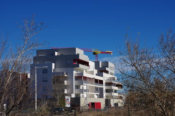 Fototapeta na wymiar Ensemble d'immeuble moderne de logement blanc et rouge en construction avec ciel bleu