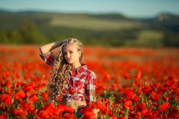 Fototapeta na wymiar Young blonde in a red shirt in the poppy flower field.