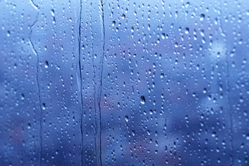 Naklejka na ściany i meble raindrops on glass window in blue background