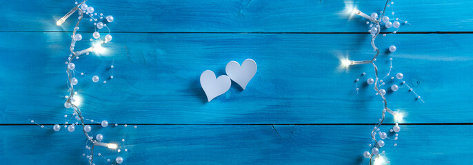 say it with love banner. sweet wooden hearts on a blue wooden background with nice light decoration as a sign of love. love embassy. Valentine's Day banner with space for text.