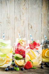 Selection various fruit and berry lemonade drinks, refreshment infused water, in mason jars, with fresh strawberry, lemon, lime, oranges, blueberry,  copy space