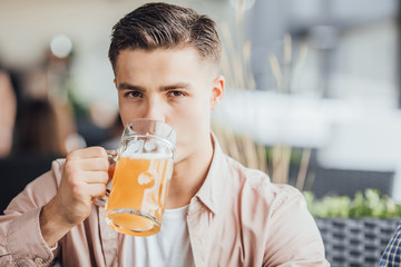 Stunning boy drinking beer at his favourite cafe