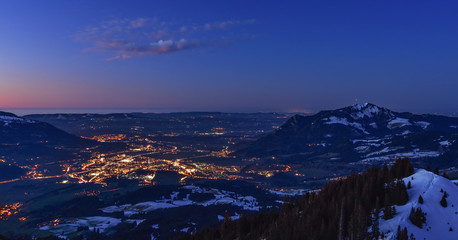 City night lights of Sonthofen (Allgaeu, Bavaria, Germany) after sunset with Gruenten mountain in winter. Landscape in twilight with blue sky and some clouds.