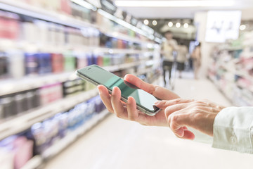Digital lifestyle business person or shopper using mobile smart phone for retail shopping in supermarket