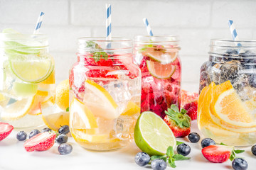 Selection various fruit and berry lemonade drinks, refreshment infused water, in mason jars, with fresh strawberry, lemon, lime, oranges, blueberry,  copy space