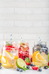 Fototapeta na wymiar Selection various fruit and berry lemonade drinks, refreshment infused water, in mason jars, with fresh strawberry, lemon, lime, oranges, blueberry, copy space