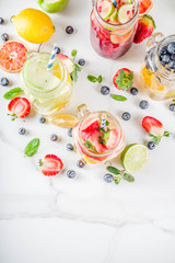Selection various fruit and berry lemonade drinks, refreshment infused water, in mason jars, with fresh strawberry, lemon, lime, oranges, blueberry,  copy space