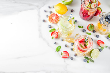 Selection various fruit and berry lemonade drinks, refreshment infused water, in mason jars, with fresh strawberry, lemon, lime, oranges, blueberry,  copy space