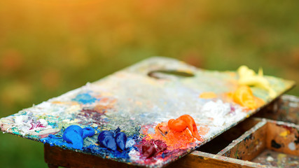Acrylic colors on a dirty palette. Macro artist's palette. Artist paints a picture of oil paints. Wooden art palette with paint and brushes, close up. Art therapy.