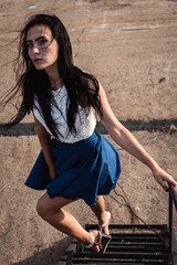 Portrait of young fashionable brunette woman practicing model posing outdoors against urban style background of grey concrete wall stairway