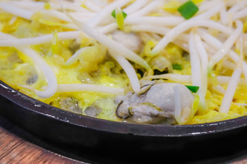 Asian eating Thai food, Frying crispy Oyster in a hot iron plate, decorated on the top with bean sprouts and spring onion cut. Served with spicy sauce or ketchup.Thai name is Hoi-Tod. .