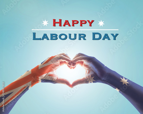 Happy labour day celebration with Australia national flag pattern on people’s hands in heart shape against blue sky background