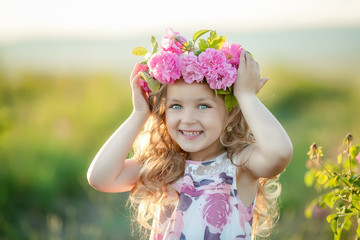 Smiling baby 3-4 year old standing with basket of flowers outdoors. Looking at camera. Summer season.