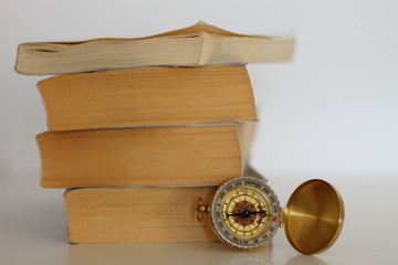 Compass on pile of old books.