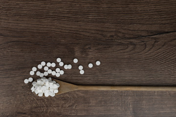 Wooden spoon filled with pills on wooden table