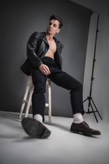 Men's model test in the studio. Young brutal man posing on a gray background. Fashion filming. Model shooting. Dressed in the classic style