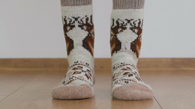 Close-up of woman's legs in warm woolen socks doing gymnastics lifting the body up with toes