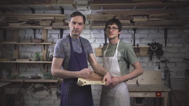 Two master carpenter in an apron in his workshop. Small business