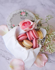 Fototapeta na wymiar Beautiful colourful macarons with flowers in round paper box on white marble background 