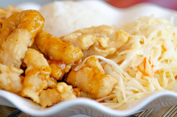 Chinese food, rice with fried chicken in soya sauce and vegetables, cabbage and carrots in a white plate, close up