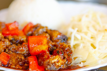 Chinese food, rice with seafood and red peppers in soya sauce and vegetables, cabbage and carrots in a white plate, close up