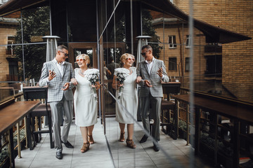 Family seniors couple standing at the terrace in modern cafe