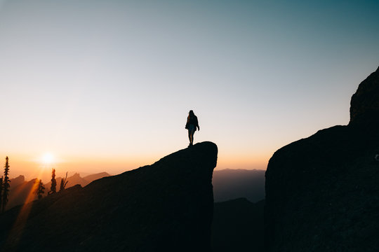 silhouette of woman on top of the mountain at sunset