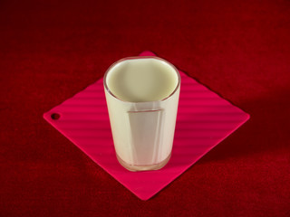 Yogurt in a glass figured glass on a red background.