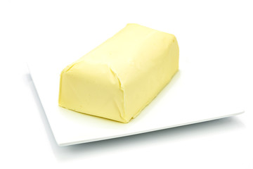 Piece of fresh organic butter on the plate isolated on a white background in close-up 