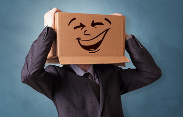 Young boy standing and gesturing with a cardboard box on his head
