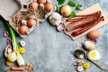 Fototapeta na wymiar Eggs, bread, smoked sausage and vegetables. Easter food on grey, stone backround.