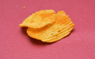 potato chips spiced with hot chili pepper on red background,