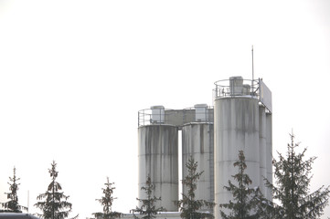 Tower of a cement plant with trees in the front