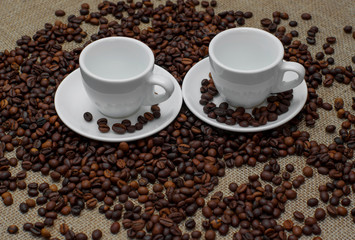 Coffee beans. Coffee cup on coffee beans. Coffee beans on burlap