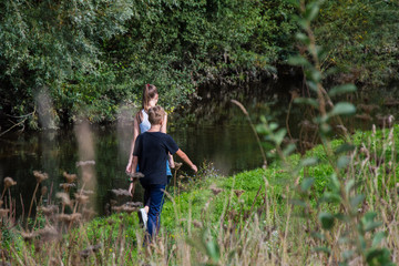 Naklejka na ściany i meble children walk in nature, along the pond