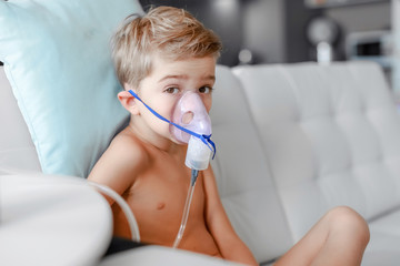sick boy in nebulizer mask making inhalation, respiratory procedure by pneumonia or cough for child, inhaler, compressor nebulizer, nebules machine for health care.