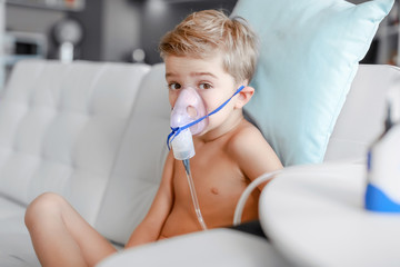 sick boy in nebulizer mask making inhalation, respiratory procedure by pneumonia or cough for...