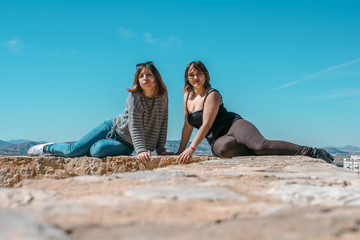 Women embrace and laugh while sitting on the castle stone