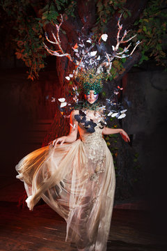 natural nymph with horns like branches of a tree and butterflies circling around. Fantasy style costume