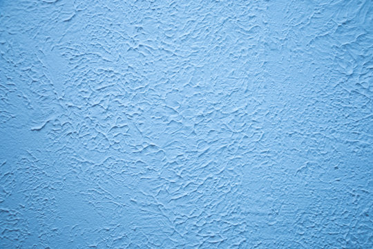 Blue textured wall. Decorative plastering close-up photo. Surface with stucco daub