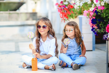 Friendly kid girl and fun emotional mother drinking berries smoothie juice together in street cafe and looking on each other. Closeup portrait