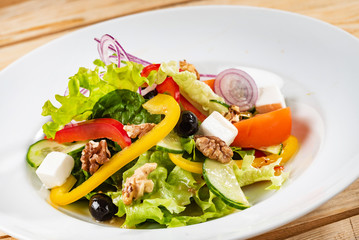 Greek salad with feta cheese on the wooden background