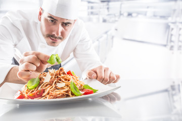 Chef in restaurant kitchen prepares and decorates meal with hands.Cook preparing spaghetti bolognese