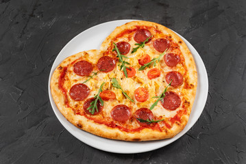 Heart shaped pizza with meat and vegetables. Food concept of romantic love for Valentines Day.