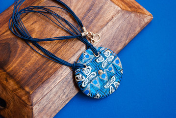 Handmade jewelry from polymer clay. Blue bright tribal pendant. Fashion background.