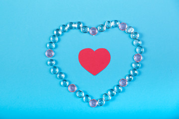 The heart of white beads and a red heart in the middle on a blue background.