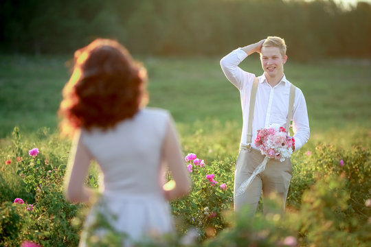 Gorgeous bride and stylish handsome groom, rustic couple in a rose field