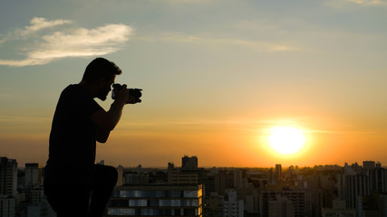 Photographer on top of a building registering the sunset in the city